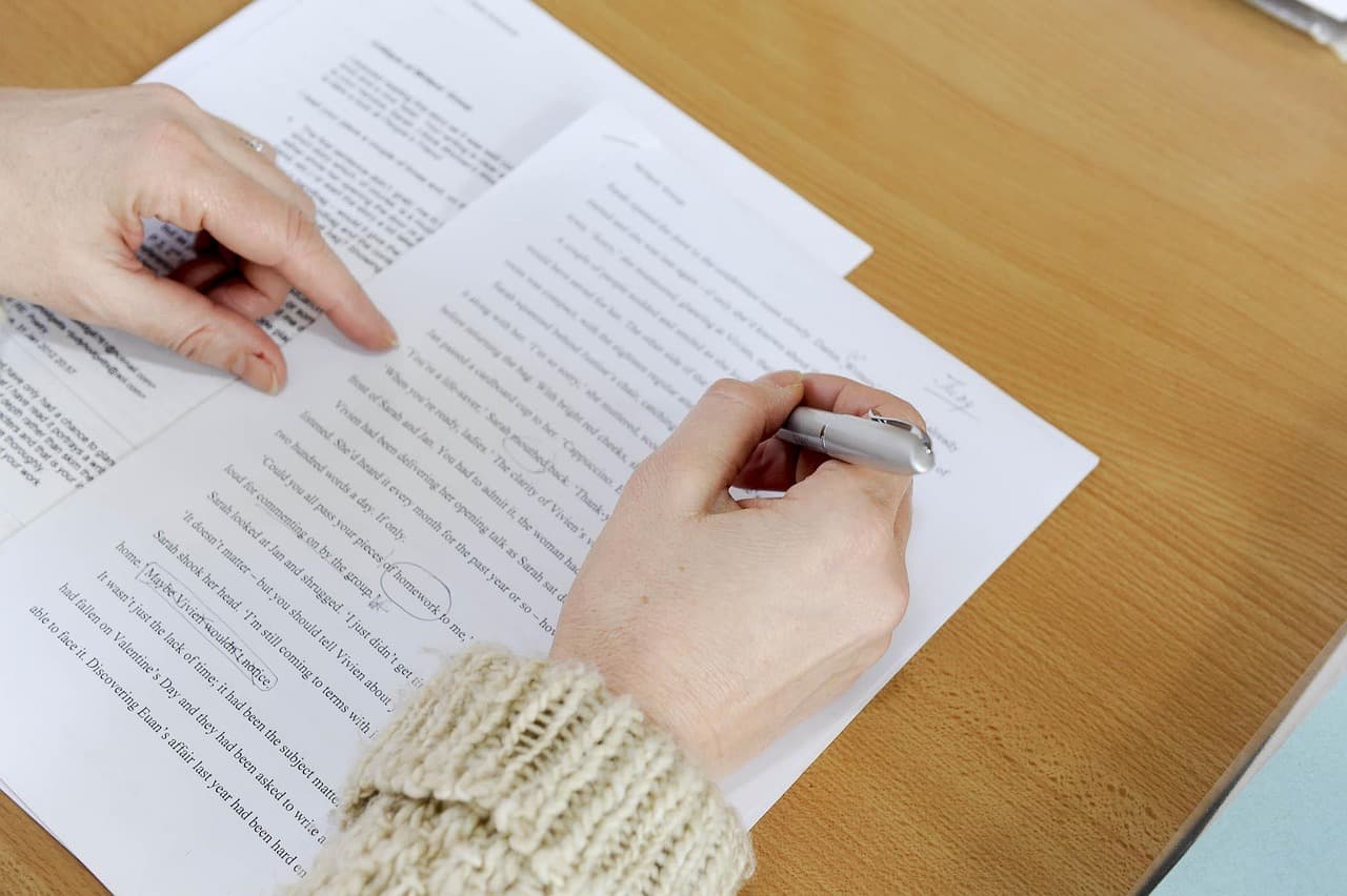 A person reviewing and editing a printed document with careful attention